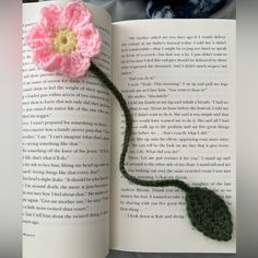 an open book with a crocheted flower on it