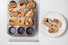 a muffin tin filled with pastries next to a plate full of jelly doughnuts