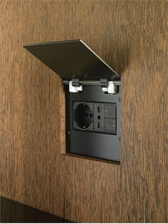 an electrical outlet is mounted on the side of a wooden wall with a black cover