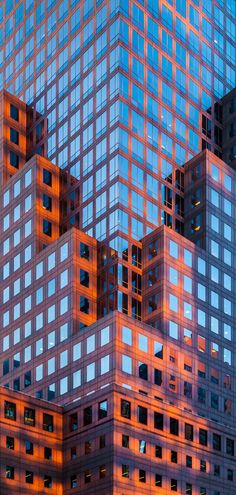 some very tall buildings that are next to each other in the evening sun with windows reflecting off them