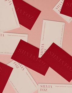 several red and white business cards laying on top of each other in front of a pink background