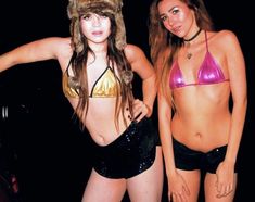 two beautiful women in bikinis standing next to each other with fur hats on their heads