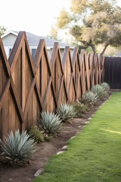 a wooden fence with succulents growing on it and grass in the foreground