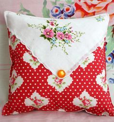 a red and white pillow sitting on top of a pink flowered wallpaper covered bed