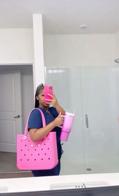 a woman is taking a selfie in the mirror with her pink purse and cup