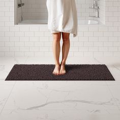 a person standing on a mat in front of a shower