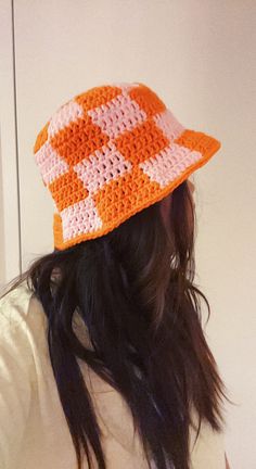 a woman wearing a crocheted hat with an orange and white design on it