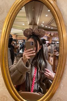 a woman taking a selfie in front of a mirror with minnie mouse ears on her head