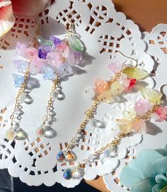 three pairs of earrings on a doily next to a flower vase with flowers in it