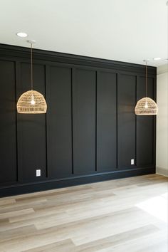 an empty room with two lamps hanging from the ceiling and wood flooring on the walls