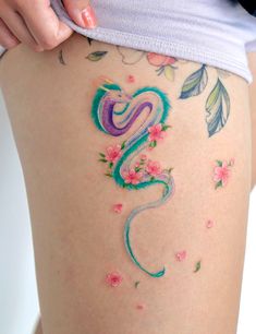 a woman's thigh with colorful tattoos and flowers on her thighs, showing the number two