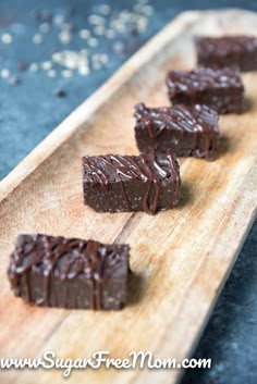 four pieces of chocolate fudge on a wooden cutting board with sea salt scattered around it