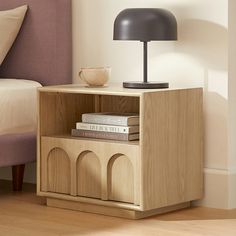 a nightstand with books and a lamp on it