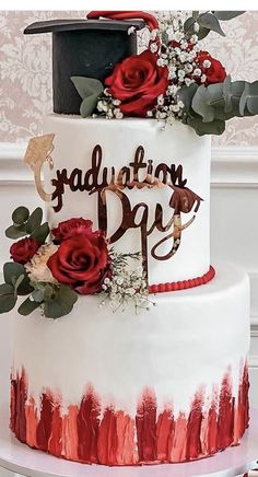 a white and red graduation cake with flowers on top