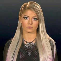 a woman with long blonde hair wearing a black top and silver necklace on her neck