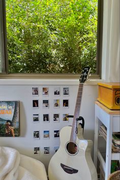 a white guitar sitting in front of a window