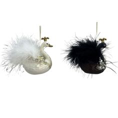 two white and black ornaments hanging from strings with feathers attached to each ornament