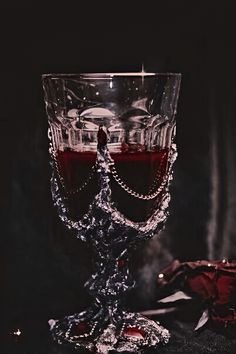 a glass filled with red liquid sitting on top of a black table next to a cloth