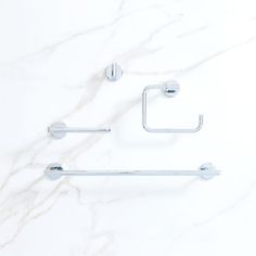 two chrome bathroom accessories on a white marble surface