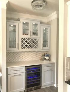 a kitchen with white cabinets and blue lights on the oven door is lit by a crystal chandelier