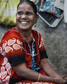 a woman sitting on the ground smiling at the camera with ear buds in her ears