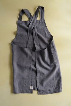 an apron made out of grey linen on a yellow surface with straps hanging down from the back