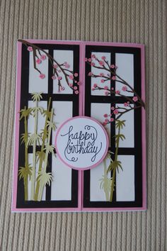 a happy birthday card with pink flowers and bamboo branches in front of a black window