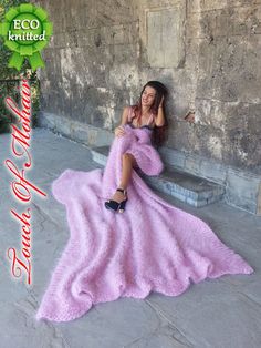 a woman in a pink dress is sitting on a stone bench and posing for the camera