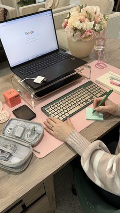 a woman sitting at a desk with a laptop computer and other office supplies on it