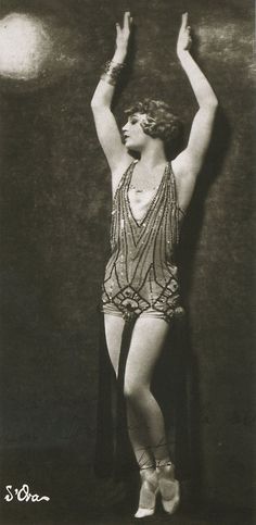 an old black and white photo of a woman in flapping clothes with her arms up