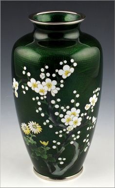 a green vase with white flowers painted on it