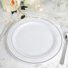 a white table setting with silverware and flowers