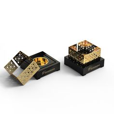 two black and gold boxes sitting on top of each other, one has a ring in it