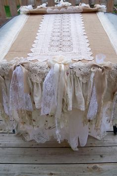 the table is covered with lace and burlaps on top of wood planks