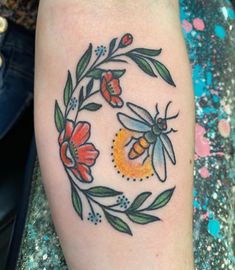 a bee and flower tattoo on the right arm with an orange ring around it's center