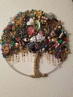 a tree made out of jewelry hangs on the wall