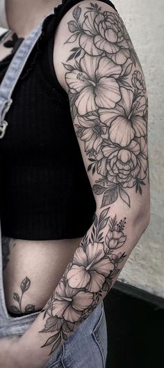 a woman's stomach with flowers on it and an arm tattoo in black ink