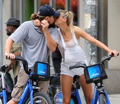 a man and woman riding bikes down the street