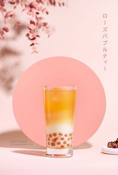 a glass filled with liquid sitting on top of a white table next to a pink plate