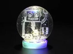 a glass ball with a robot on it sitting on a black surface in the dark