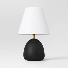 a black table lamp with a white shade on it