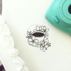 a drawing of a cup of coffee with flowers on it next to a green camera