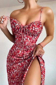 a woman in a red floral print dress with her hand on her hip, posing for the camera