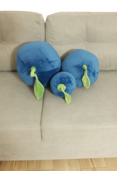 two blue pillows sitting on the back of a couch in front of a wooden floor