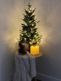 a small christmas tree sitting on top of a table next to a lit candle holder