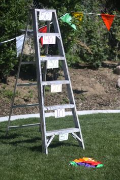 a ladder with numbers on it sitting in the grass next to some kites and bunting