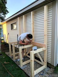 a man is working on the side of a house that's being built with wood