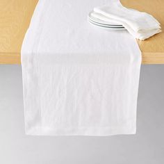 a white table runner on top of a wooden table with two plates and napkins