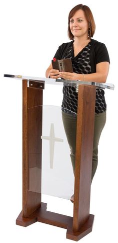 a woman standing at a podium with a book in her hand and a cross on it