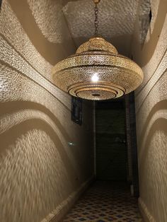 a light hanging from the ceiling in a hallway with tiled flooring and wallpaper